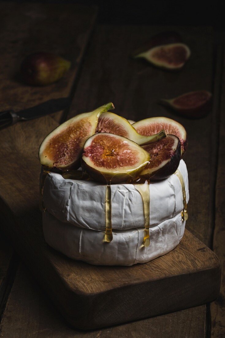 Camembert cheese with honey and fresh figs on wooden chopping board