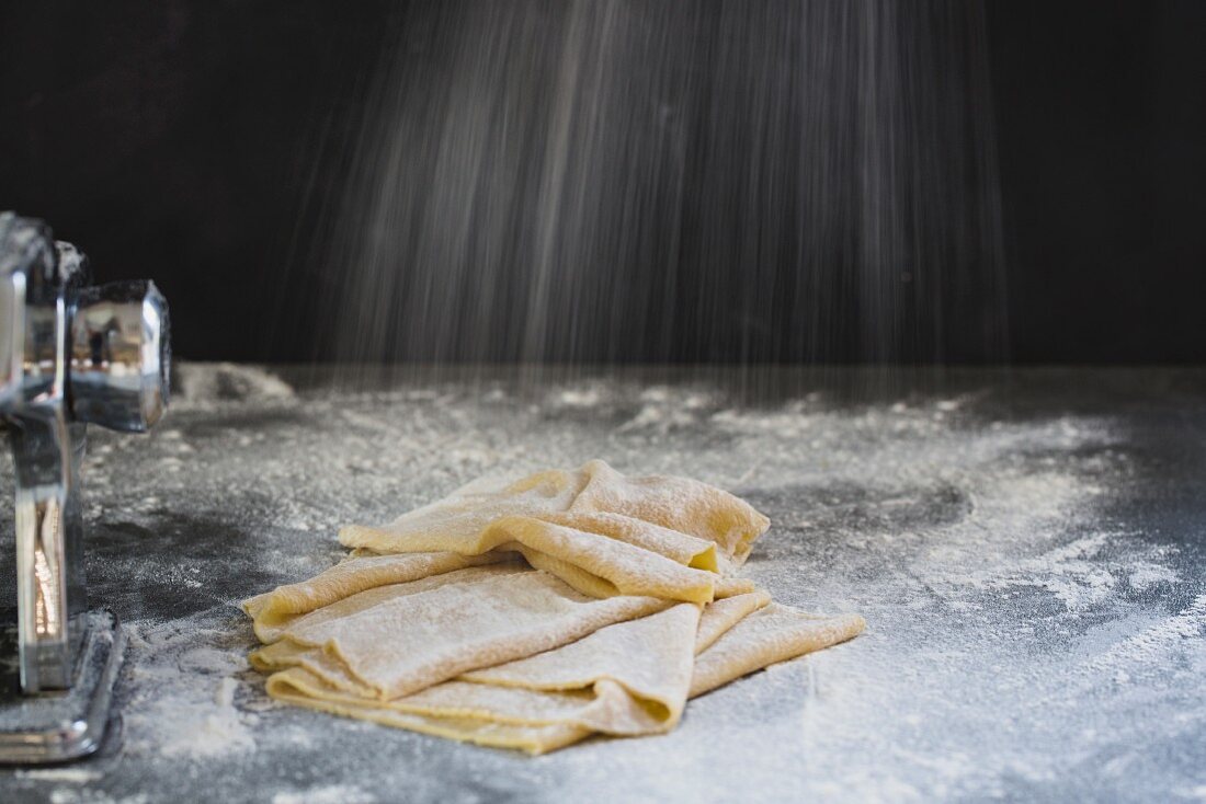 Fresh pasta dough being sprinkled with flour