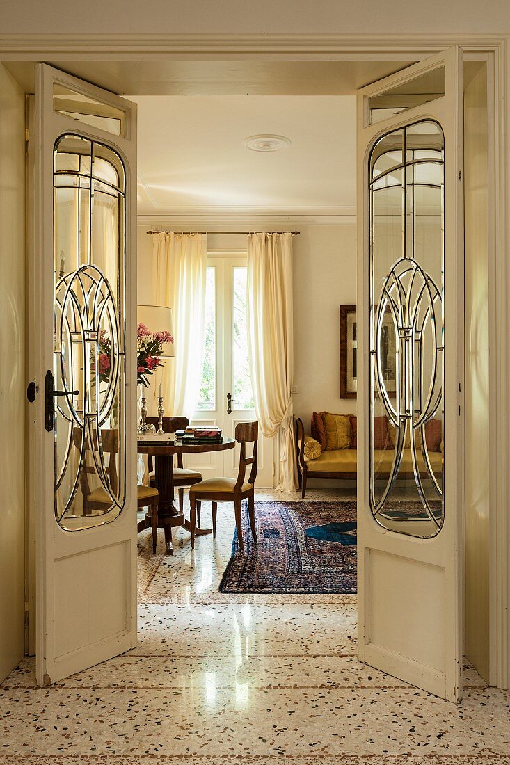 Open Art-Nouveau double doors with glass panels and view into elegant interior with exotic-wood furniture