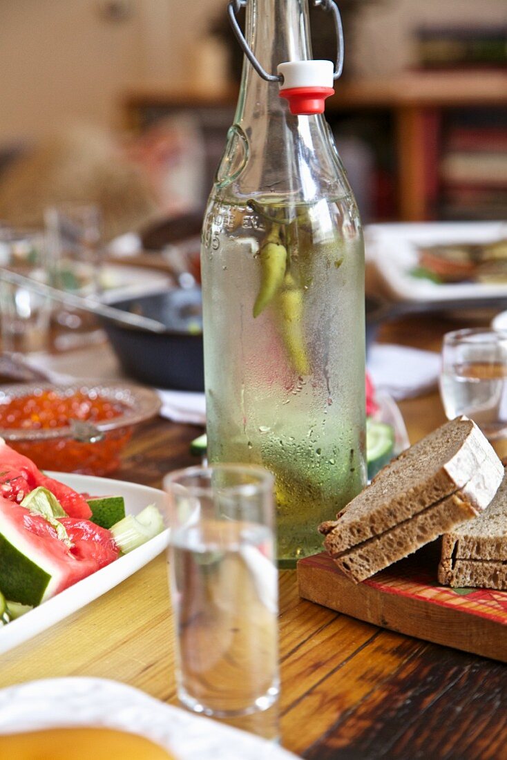 Hausgemachter Wodka mit Peperoni auf gedecktem Tisch (Russland)