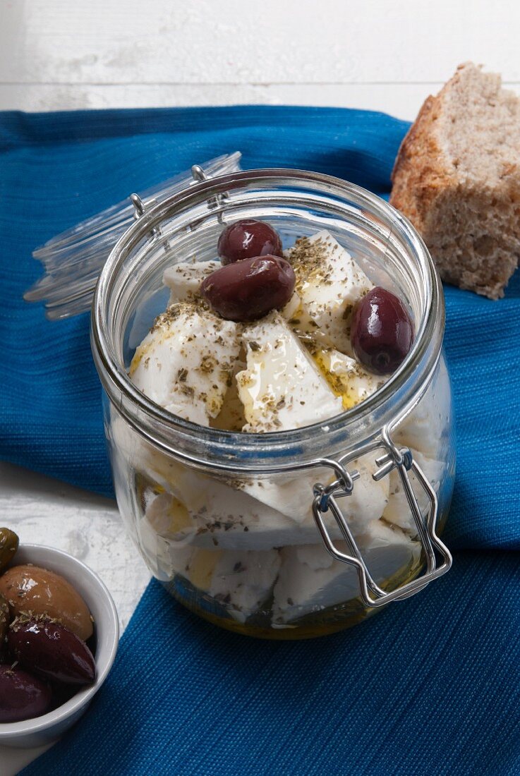 Marinated feta cheese in a preserving jar with oregano, olive oil and kalamata olives