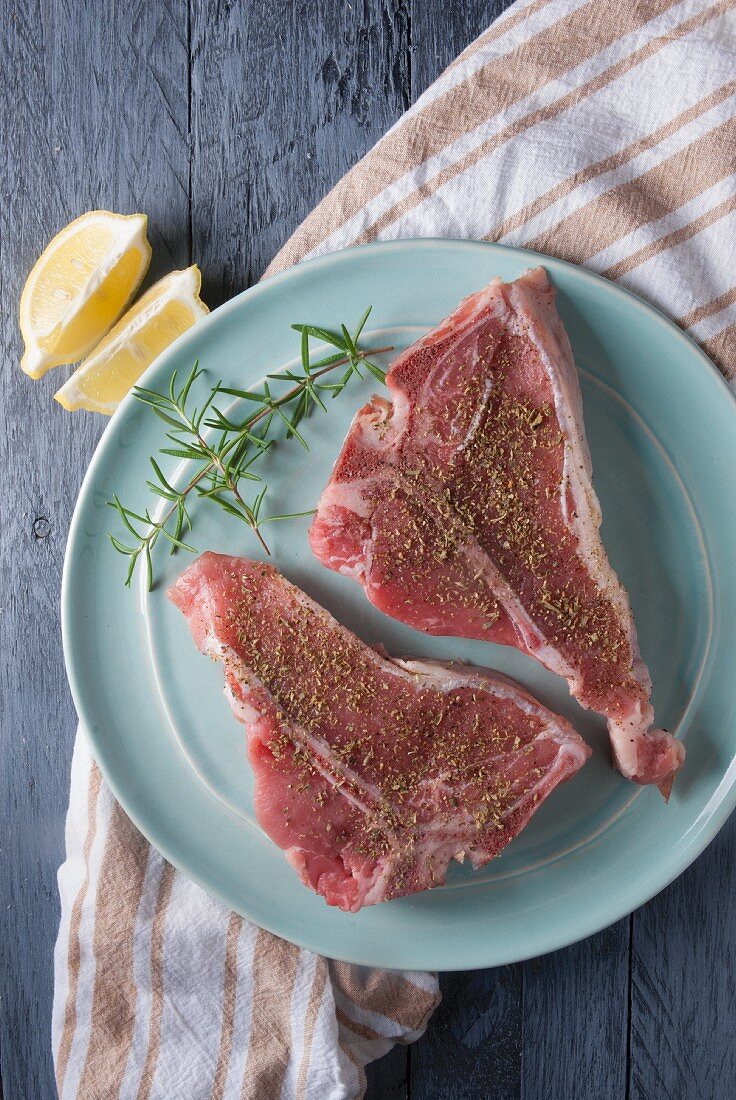 Two seasoned veal chops on a plate (seen from above)