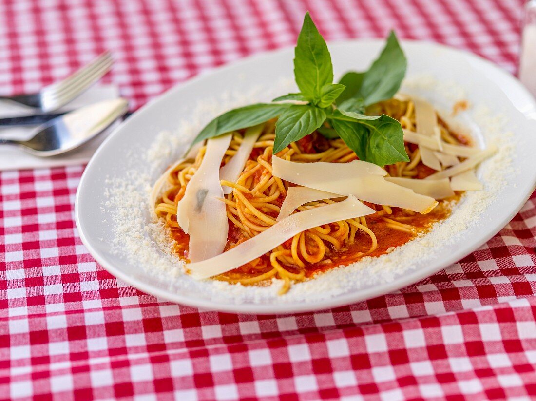 Spaghetti mit Tomatensauce und Parmesan auf kariertem Tischtuch