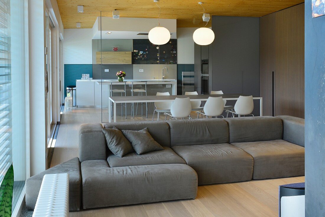 Comfortable sofa in open-plan designer living area with view of kitchen through glass partition wall