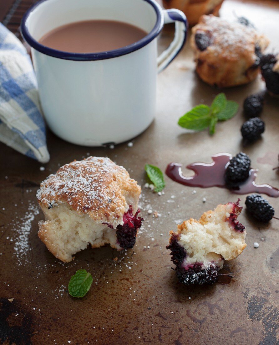 Frisch gebackene Maulbeermuffins, angebrochen, und Kaffee