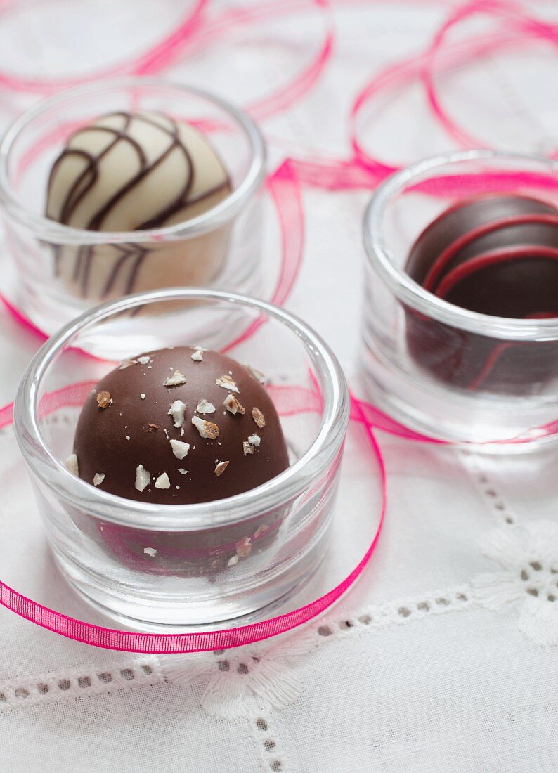 Drei Schokoladenpralinen in Glasschalen zum Valentinstag