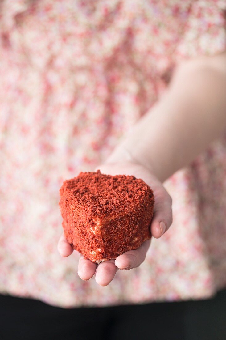 Frau hält einen Red Velvet Herzkuchen in der Hand