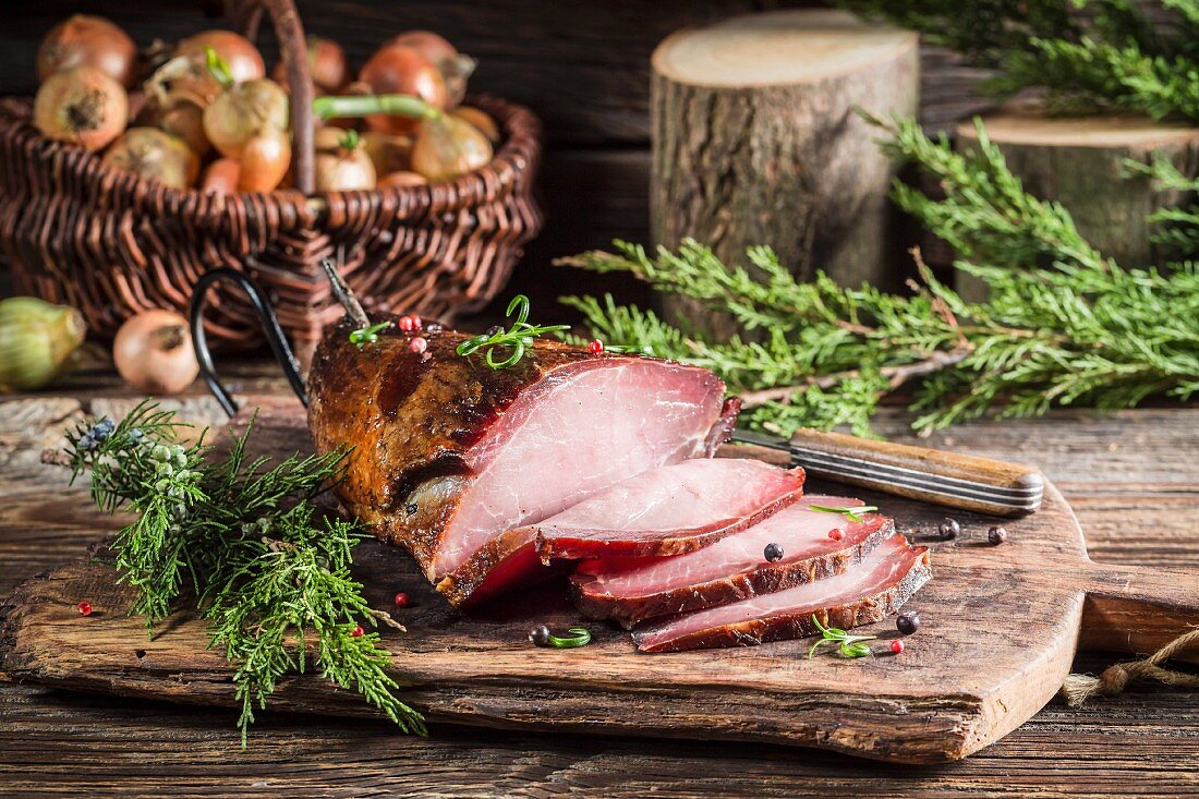 Geräucherter Schinken mit Wacholder auf Holzschneidebrett