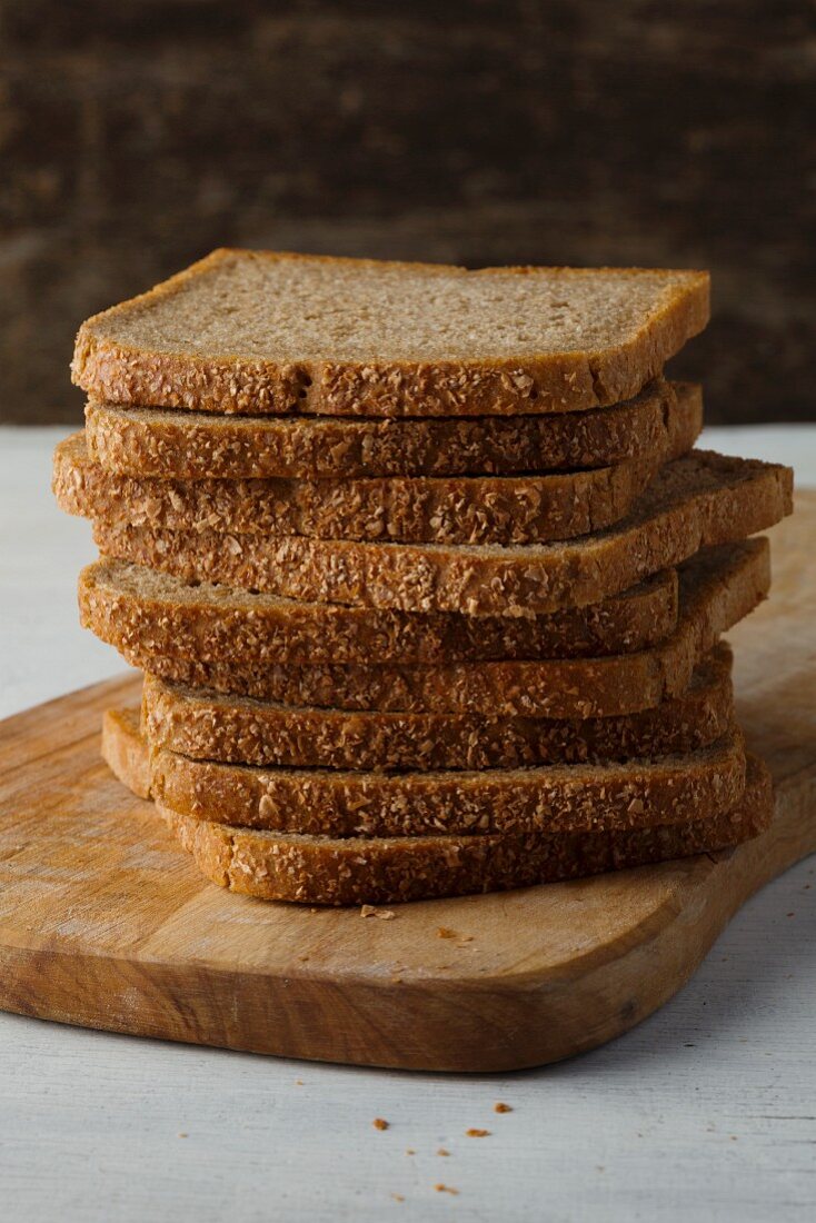 Slices of wholemeal bread stacked on a wooden board