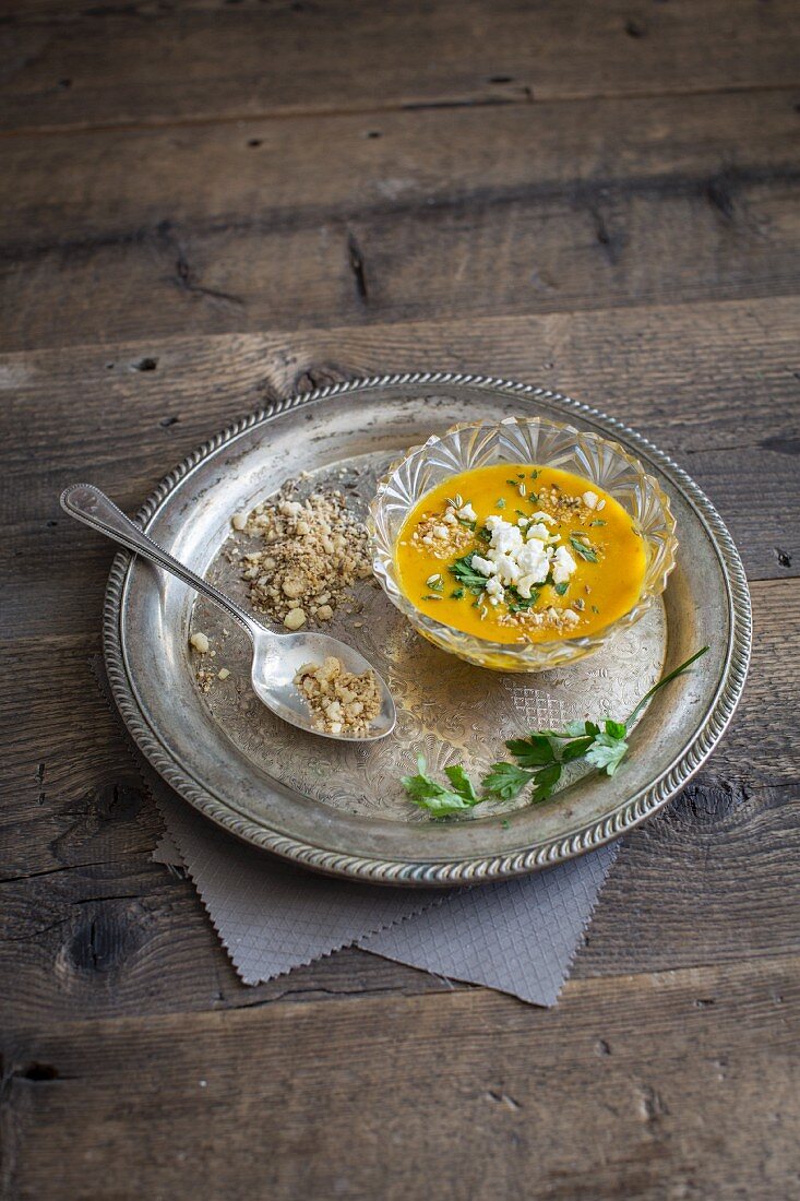 Curried carrot soup with feta cheese, spicy mixed nuts and parsley