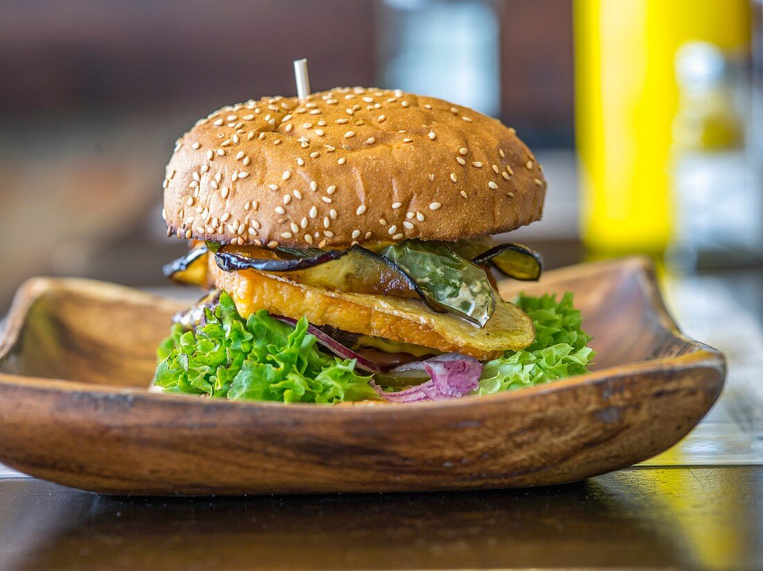 A burger on a wooden dish on a restaurant table