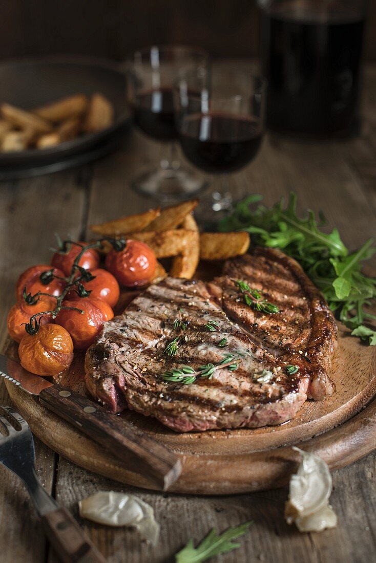 Grilled beef steak with tomatoes and chips on a wooden plate