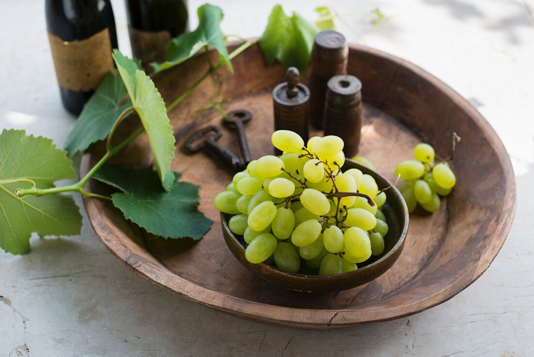 Grüne Trauben mit Weinranke und Gewürzen in Holzschale (Italien)