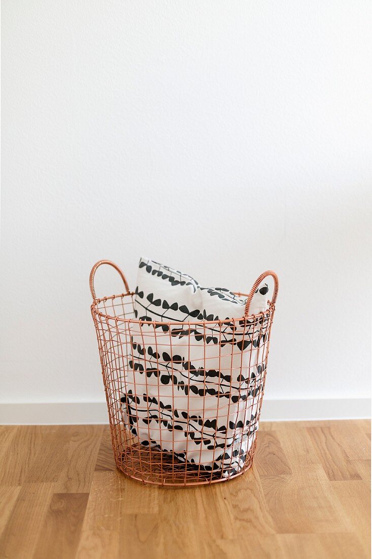 Black and white cushion in copper-coloured wire basket