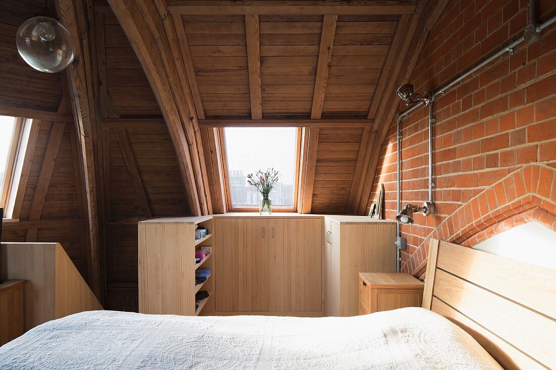 Bedroom with vaulted ceiling and modern wooden furniture in converted church