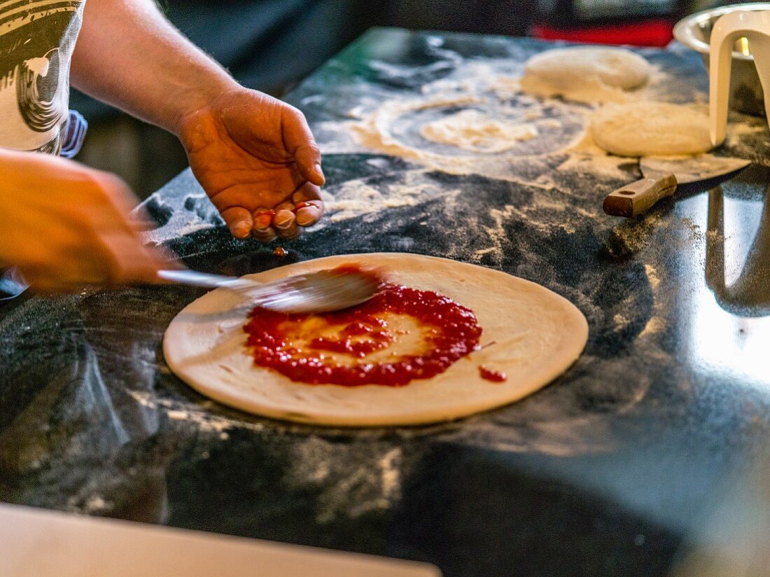 Pizzaboden mit Tomatensauce bestreichen