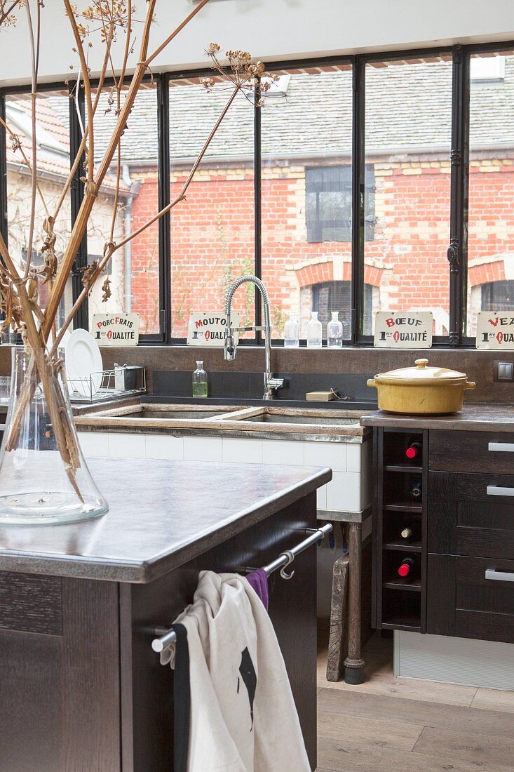 Industrial-style kitchen with view of brick house through bank of windows