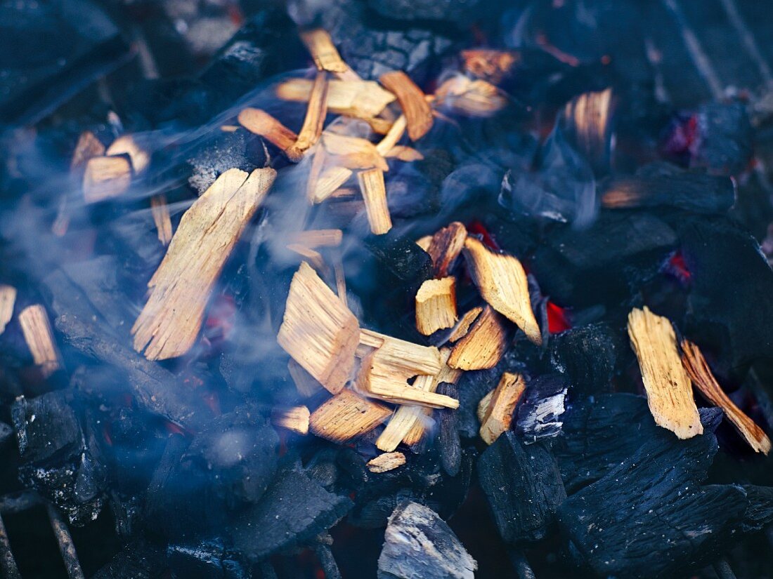 Soaked smoking chips being smoked in hot coals