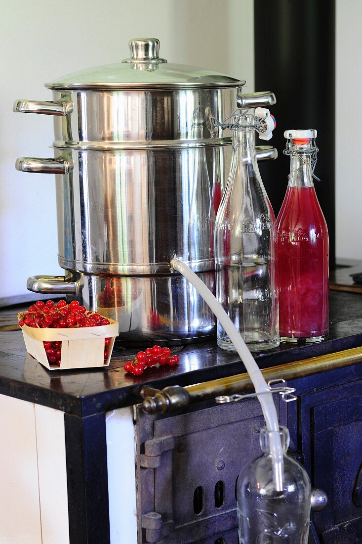 A juicer, fresh berries and bottle of juice on an old kitchen stove
