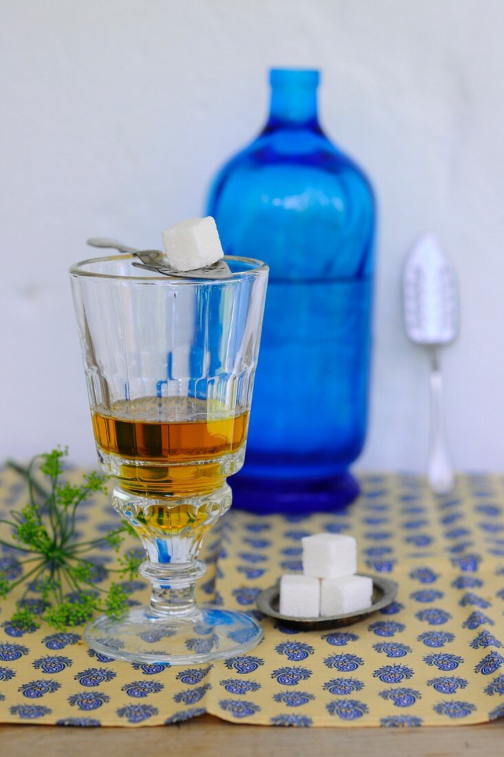 A glass of apple vinegar, a bottle of water and sugar cubes
