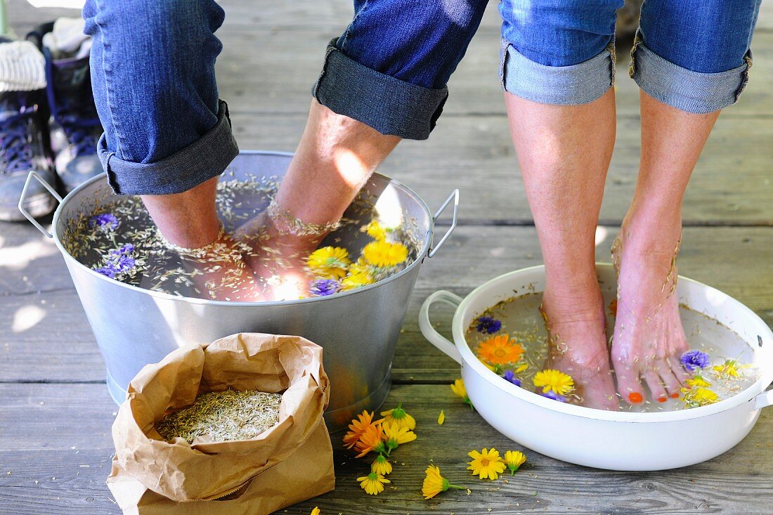 Couple bathing feet in water and medicinal flowers