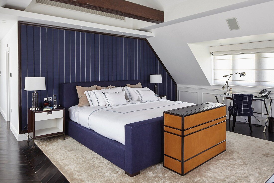 Open-plan bedroom with blue accent wall behind bed