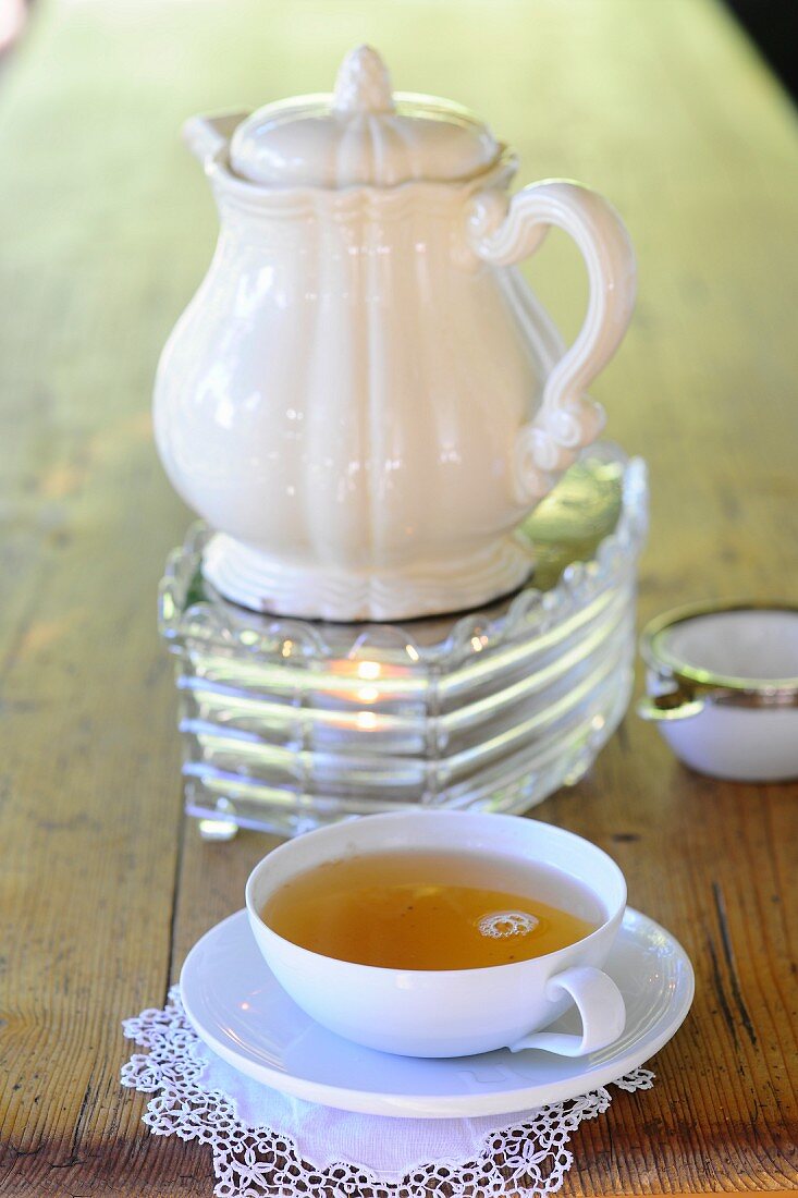 Teetasse vor Teekanne auf Stövchen