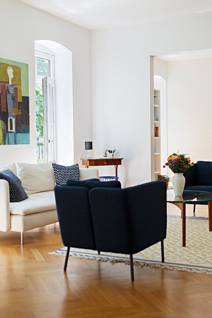 Dark blue armchairs and white sofa on herringbone parquet floor in living room