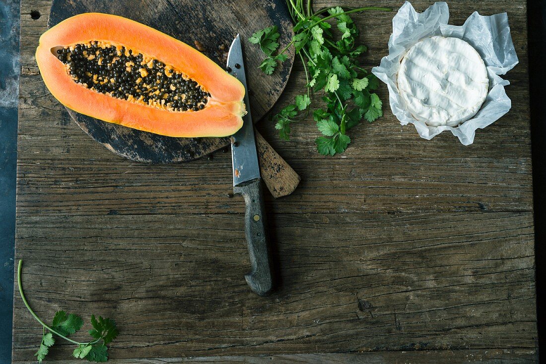 A sliced papaya, fresh coriander and Camembert