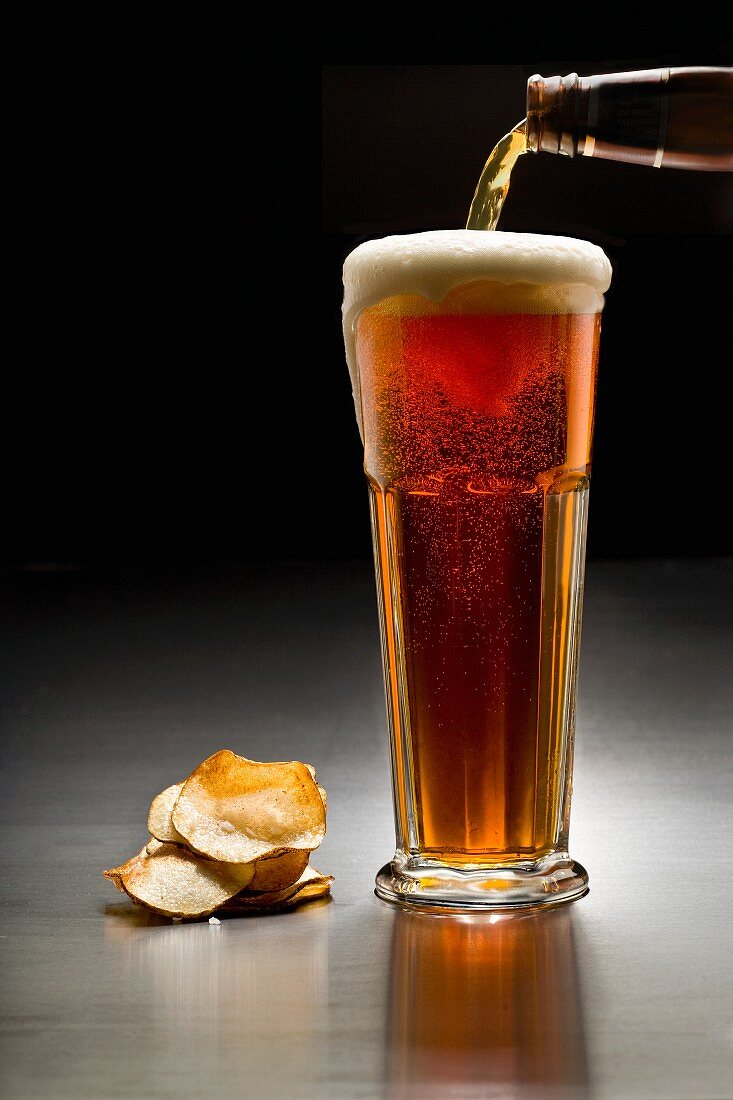 A glass of dark beer and crisps