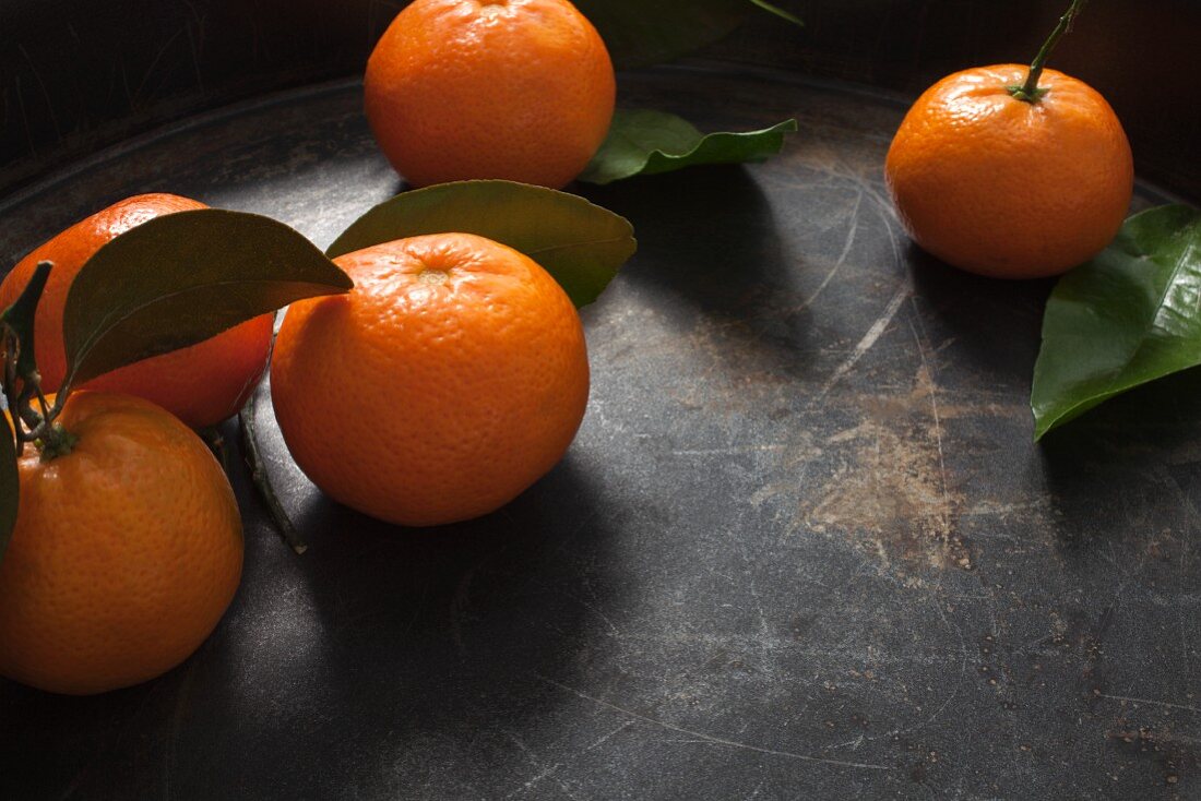 Five clementines with stems and leaves