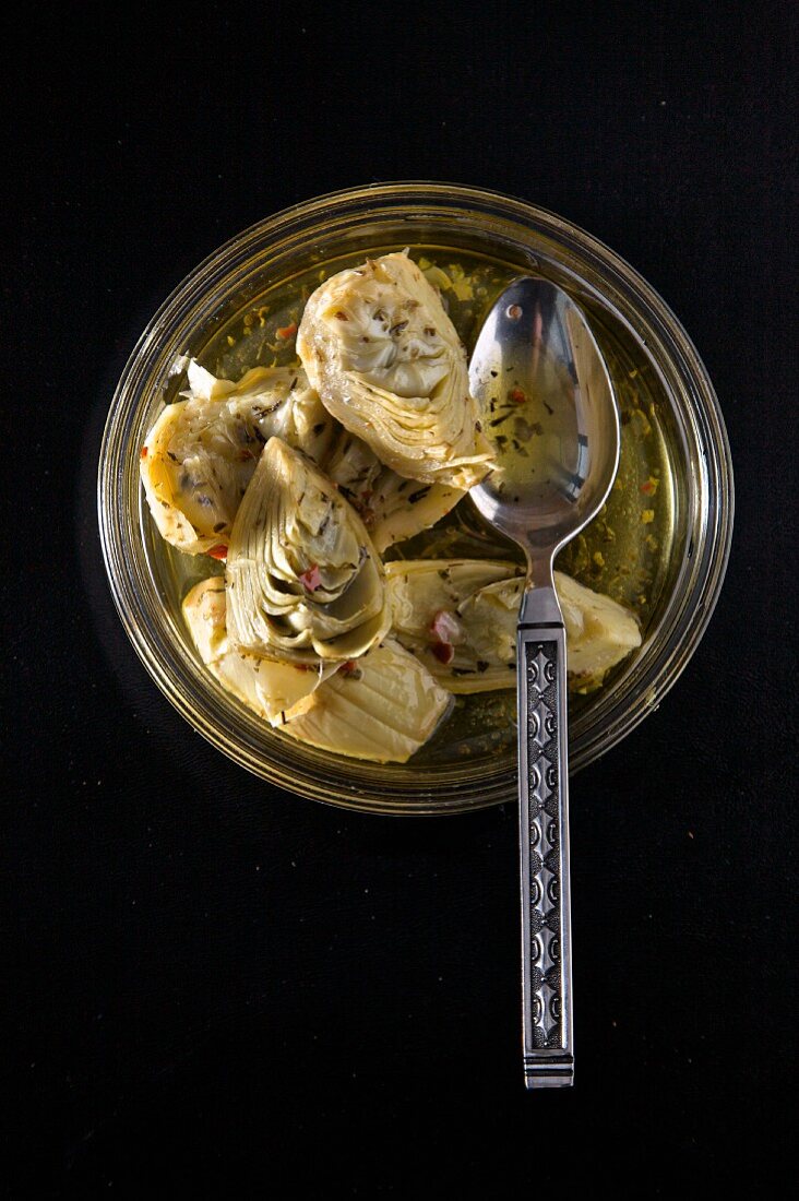Marinated artichokes in a jar with a spoon