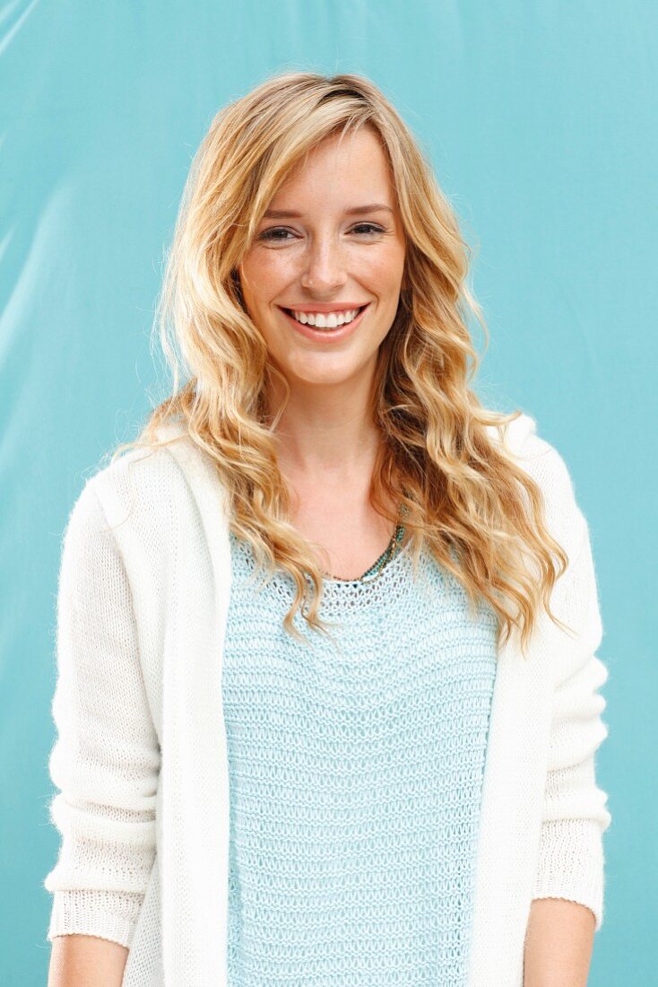 A young blonde woman wearing a knitted top and a jacket