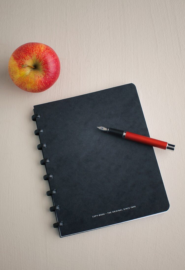 Notizbuch mit Stift und Apfel