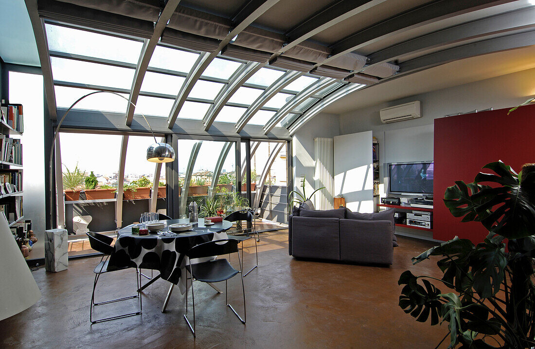 Dining area and lounge in open-plan interior with metal and glass elements