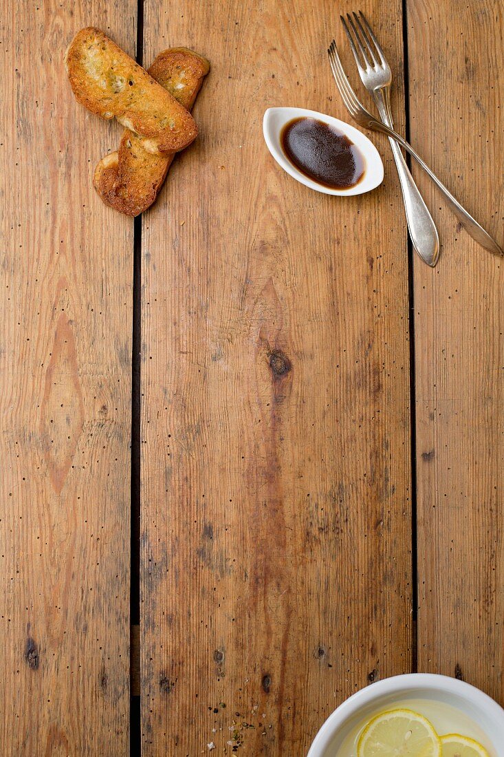 Slices of grilled bread and a bowl of balsamic dressing on a wooden table