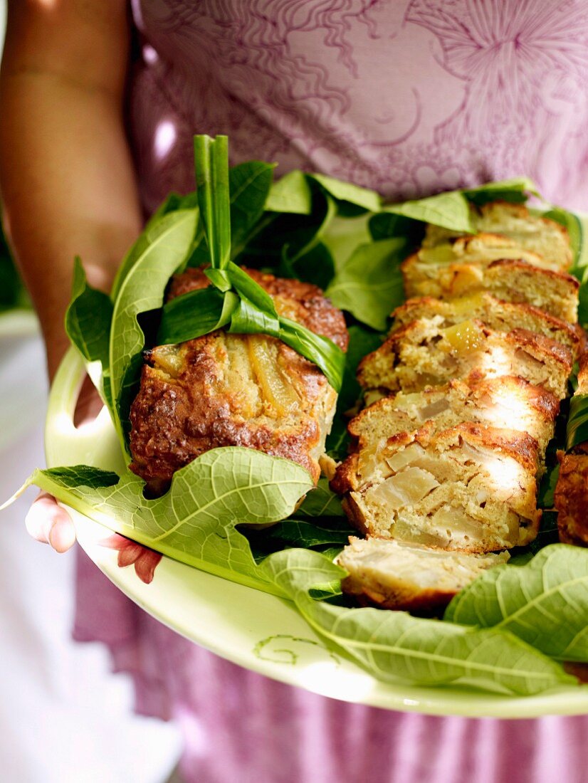 Woman holding plate of papaya bread made from green papayas (Cook Islands, South Pacific)