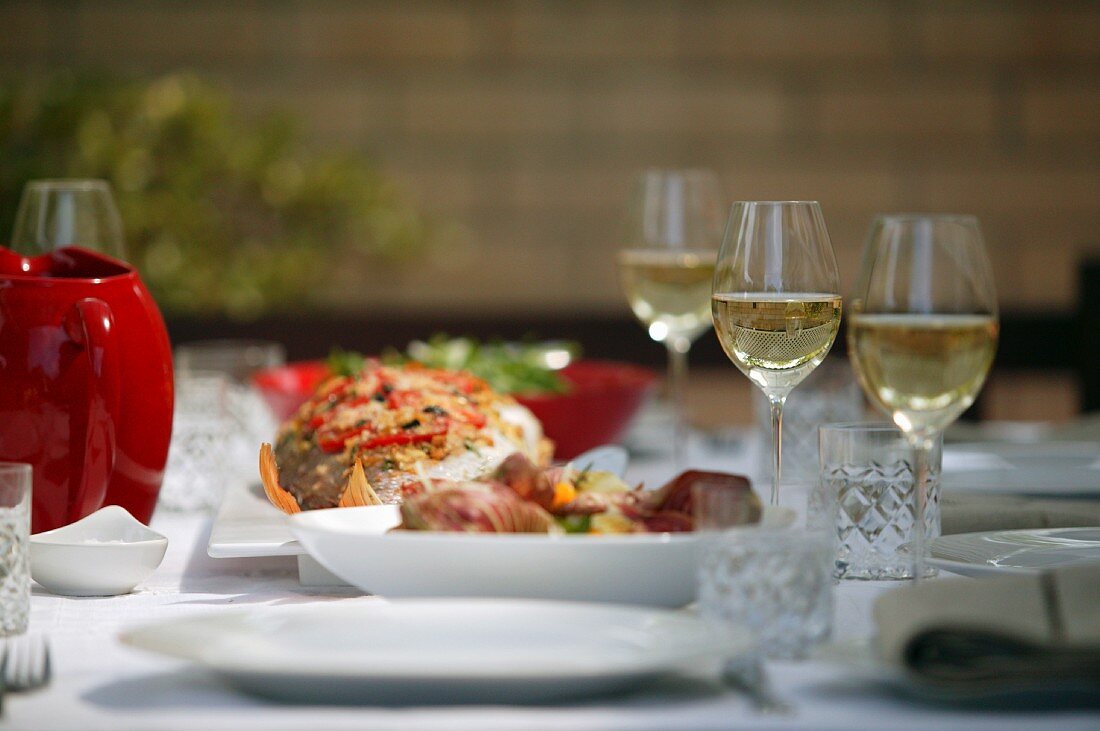 Baked Whole Fish on table with wine glasses