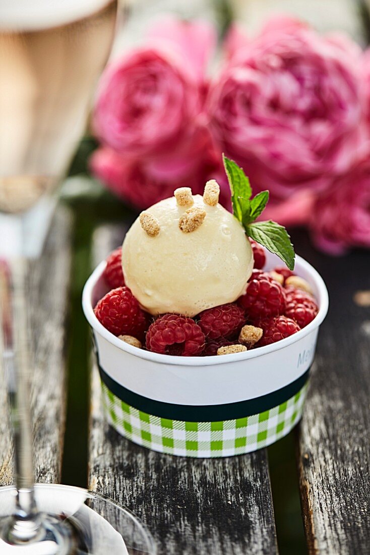 Karamell-Vanilleeis mit frischen Himbeeren auf Gartentisch