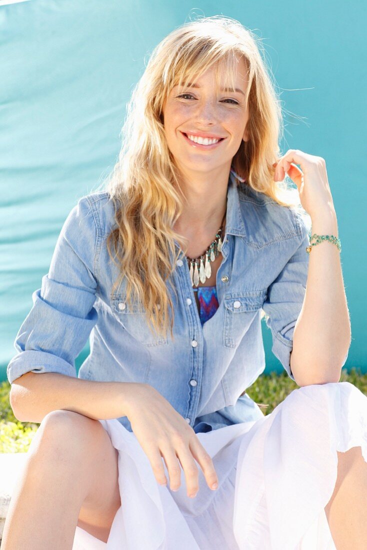 A young blonde woman wearing a denim shirt and a wide skirt