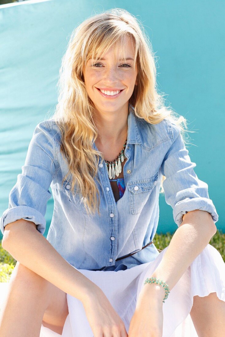 A young blonde woman wearing a denim shirt and a wide skirt