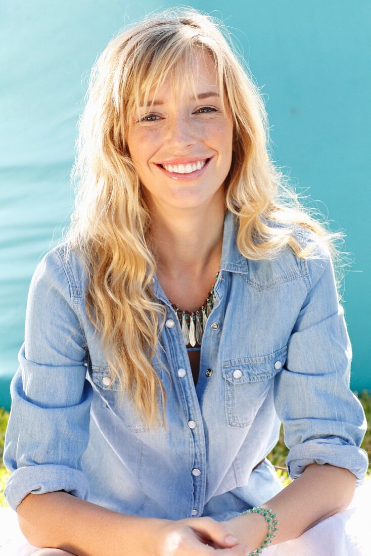 A young blonde woman wearing a denim shirt