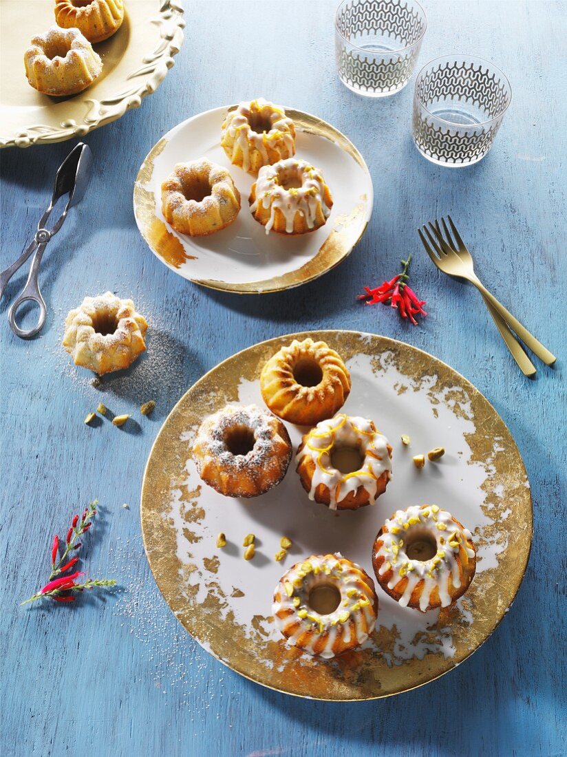 Mini Bundt cakes on gold-patterned plates on a blue wooden surface