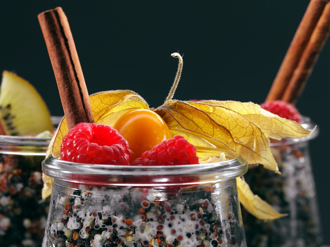 Quinoa-Frühstück mit Himbeeren, Zimtstange und Physalis in Glastöpfchen