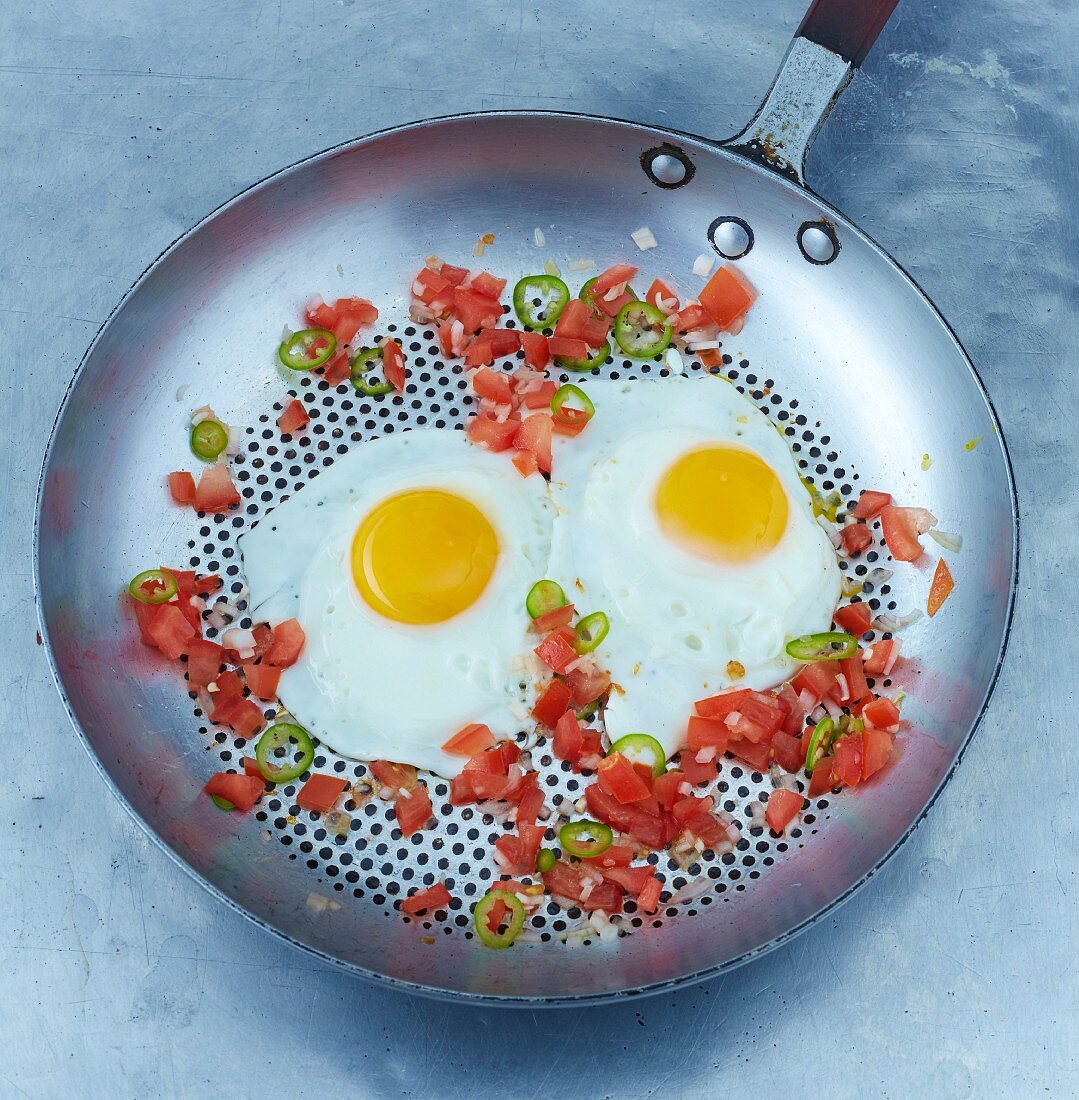 Fried eggs with chilli rings in a pan