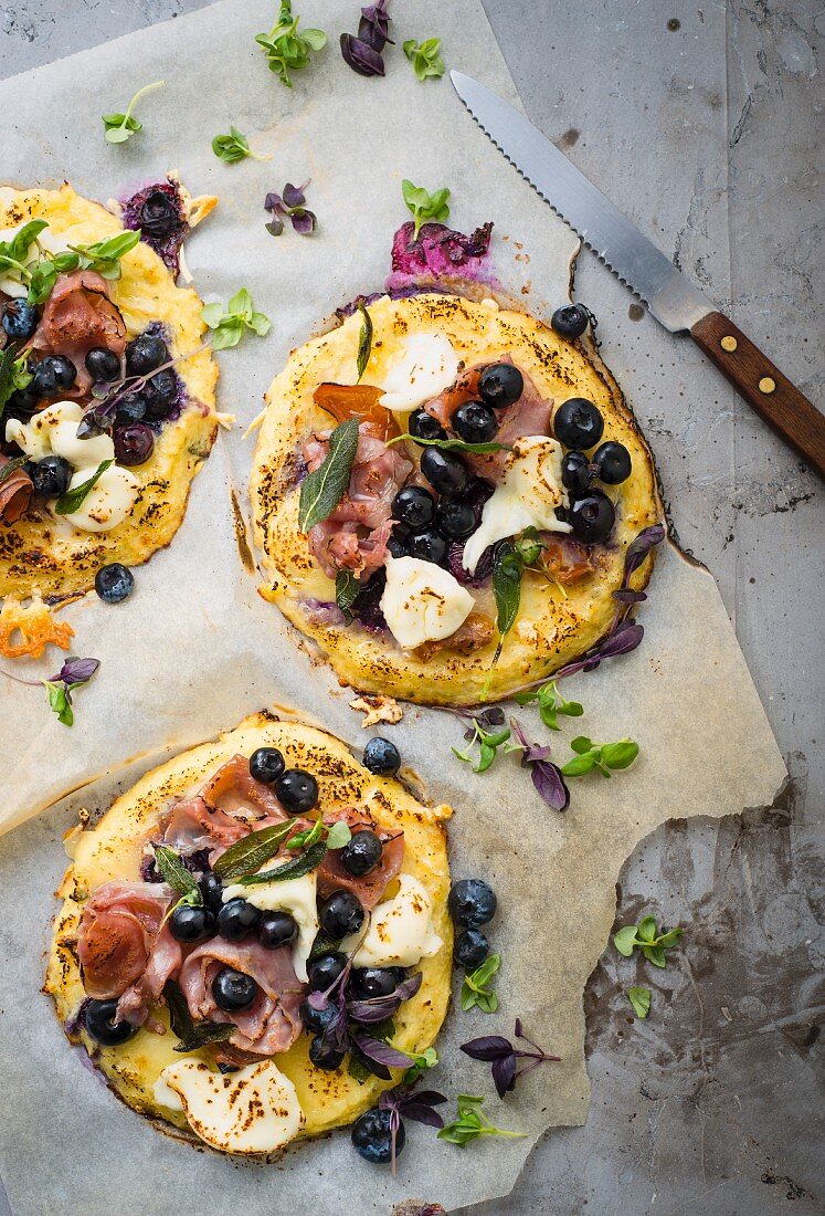 Mini pizzas with blueberries, ham, cheese and various spices