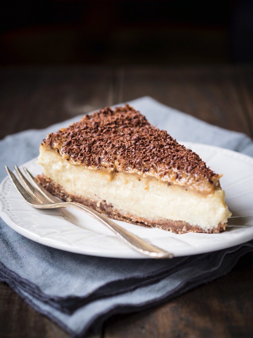 A slice of vegan millet cheesecake with date caramel on a dark surface