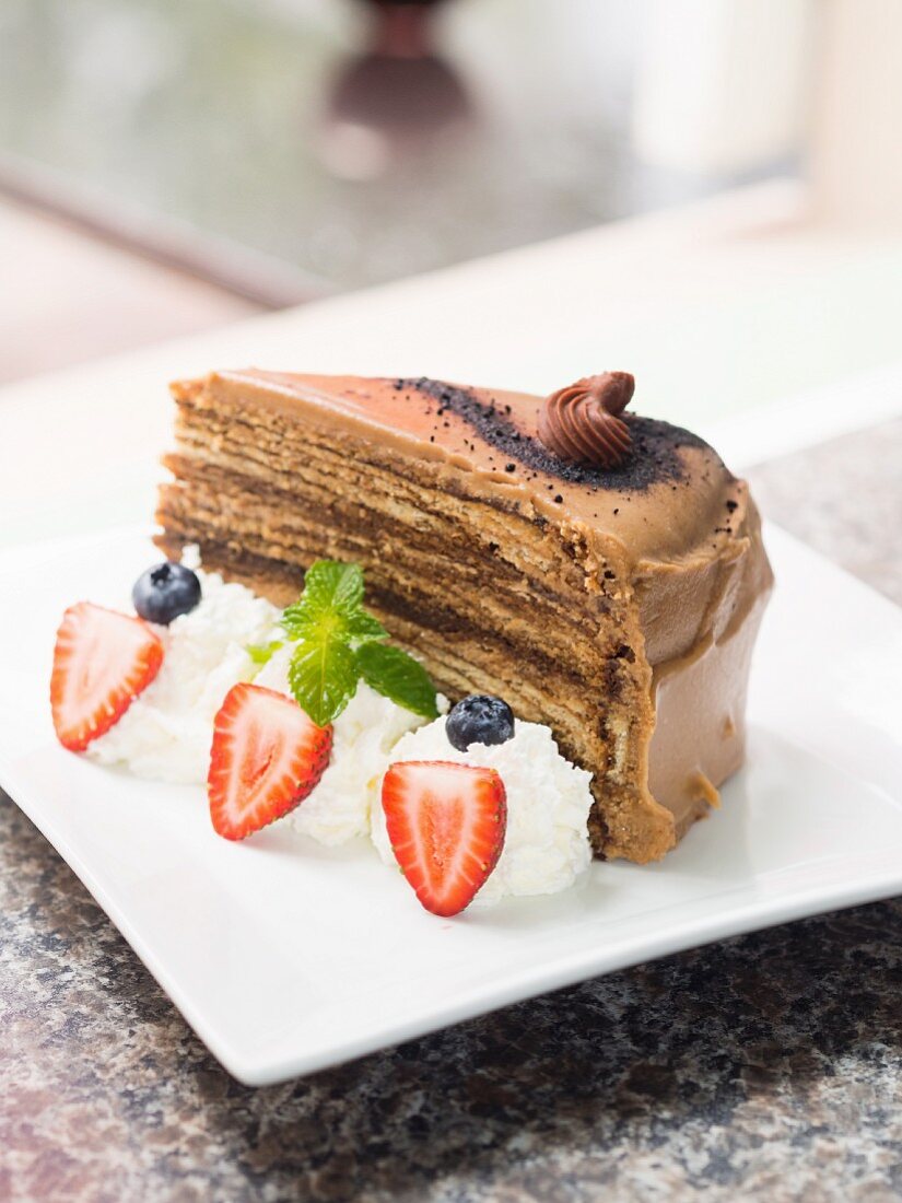 A slice of tiramisu chocolate cake served with whipped cream and berries