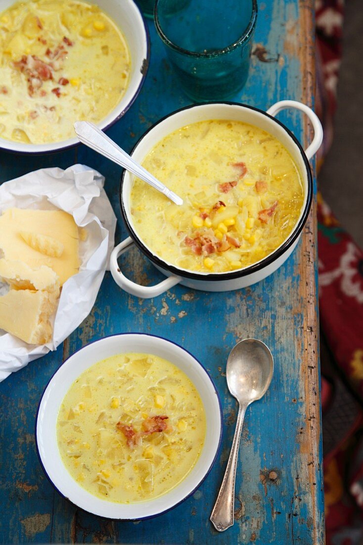 Dicke Maissuppe und Käse auf blauem Holztisch