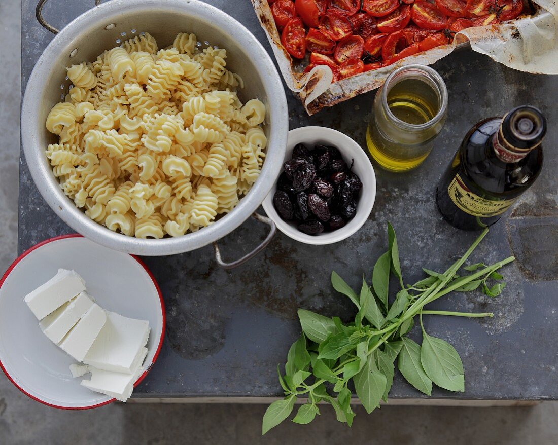 An arrangement of cooked pasta, olives, basil and olive oil